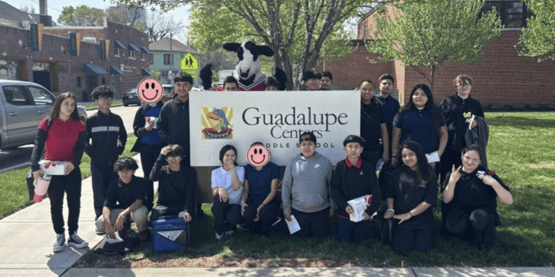 Guadalupe Centers Middle School students gathered around the school sign with their mascot