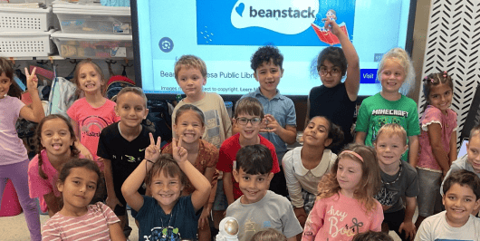 Students celebrating in front of a Beanstack reading challenge screen